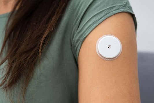 Continuous glucose monitor on an arm with the tracking app