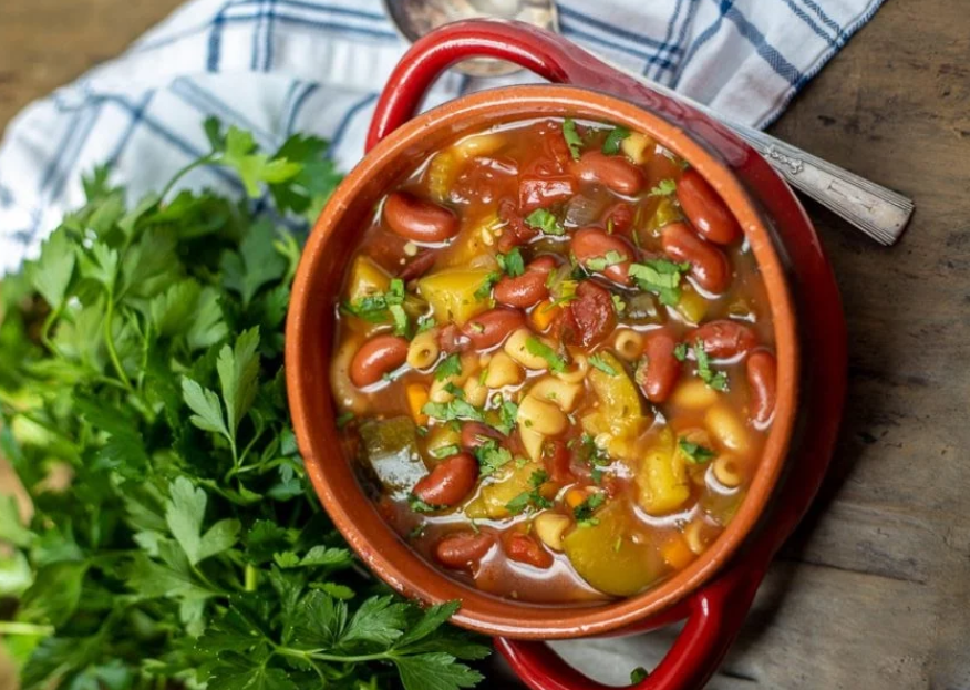 Bowl of minestrone soup and a tray of stuffed bell peppers