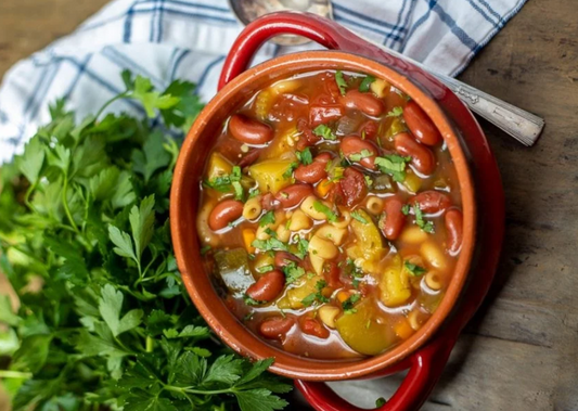 Bowl of minestrone soup and a tray of stuffed bell peppers
