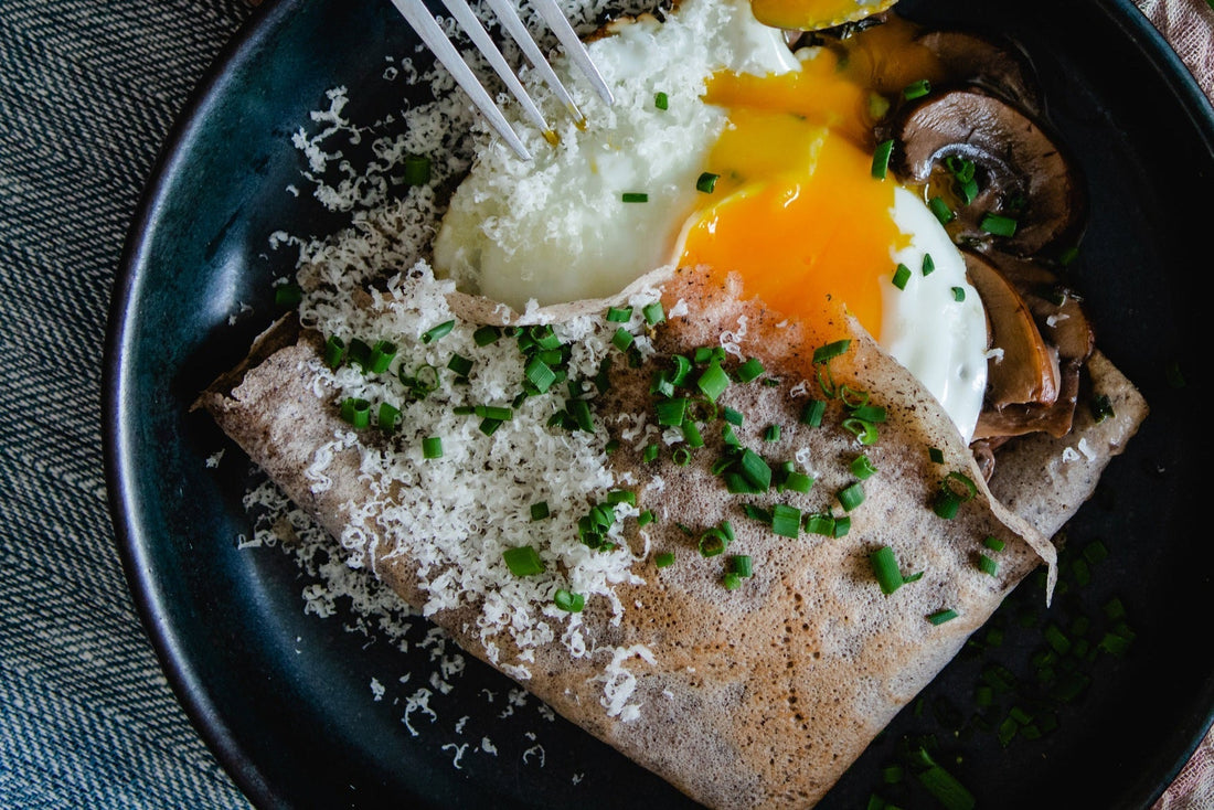 Savoury buckwheat crepes and mushroom risotto on a wooden table