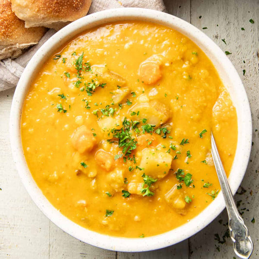 Bowl of golden yellow split pea soup garnished with parsley